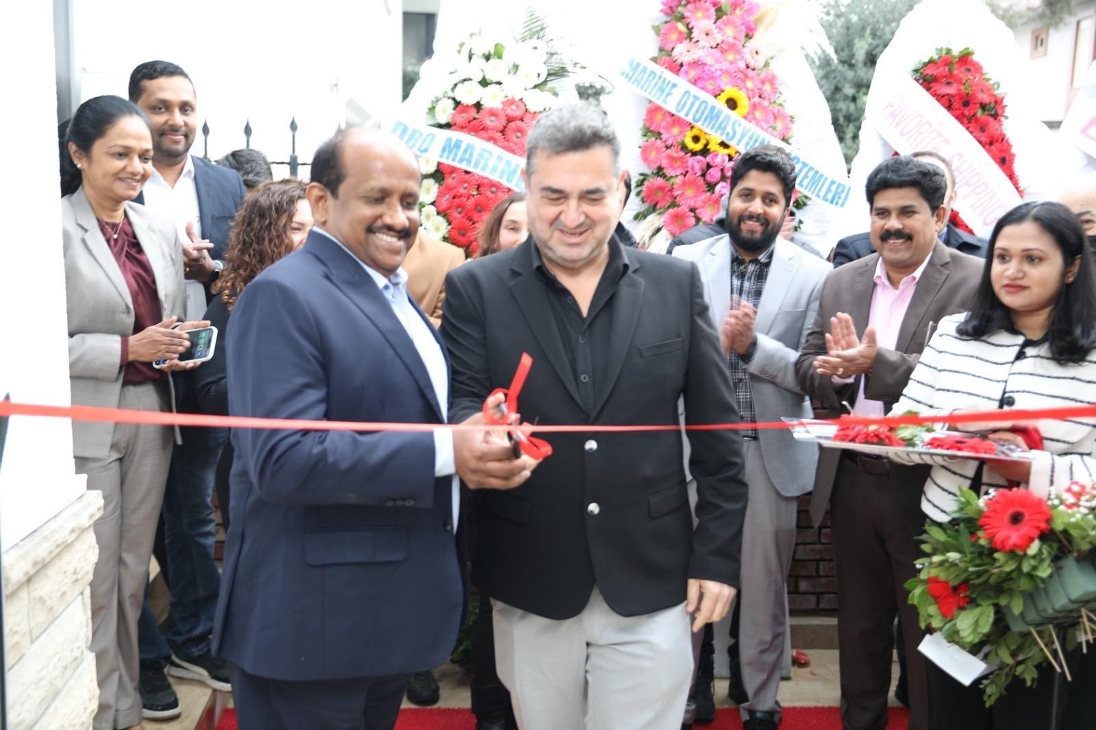A ribbon-cutting ceremony outside a modern glass building labeled "Master Systems" in Tuzla, Istanbul, featuring executives, local branding, and a view of the sea in the background.